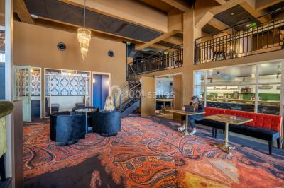 Salle de réunion avec table en bois foncé, six chaises grises, tableau blanc et écran mural.