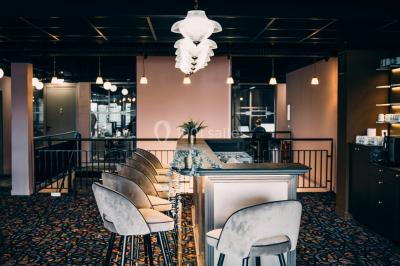 Salle de réunion avec table en bois foncé, six chaises grises, tableau blanc et écran mural.