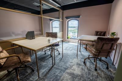 Salle de réunion avec table en bois foncé, six chaises grises, tableau blanc et écran mural.