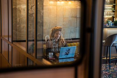 Salle de réunion avec table en bois foncé, six chaises grises, tableau blanc et écran mural.