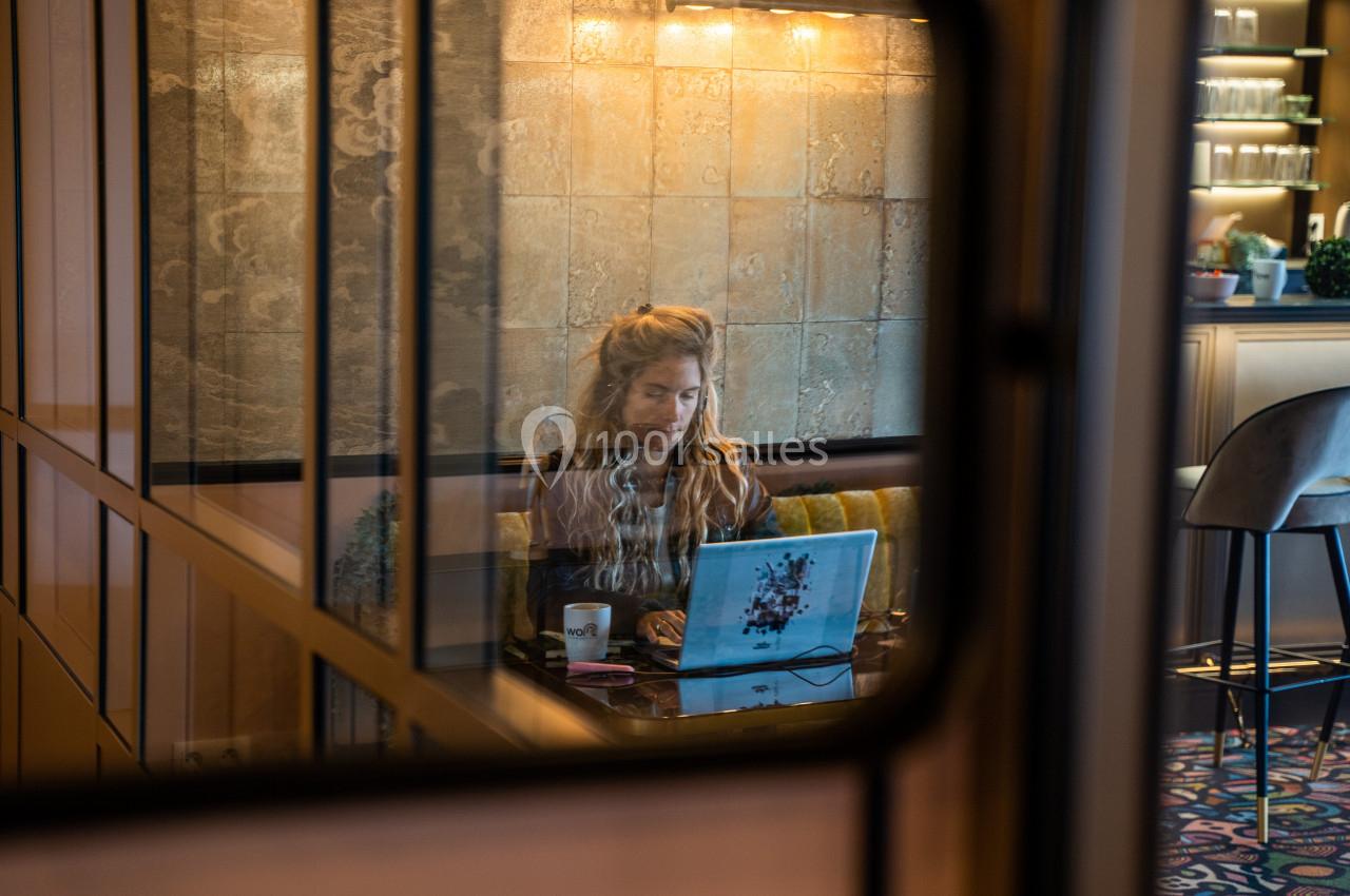 Une femme travaille sur un ordinateur portable dans un espace intérieur moderne avec des murs texturés et un éclairage doux.