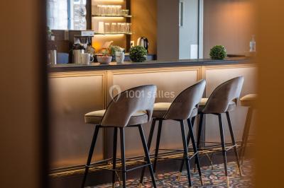 Salle de réunion avec table en bois foncé, six chaises grises, tableau blanc et écran mural.