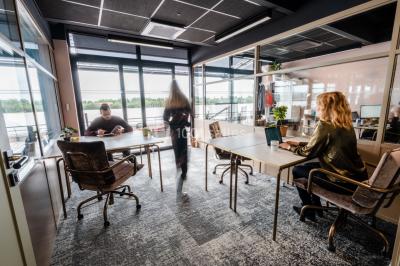 Salle de réunion avec table en bois foncé, six chaises grises, tableau blanc et écran mural.
