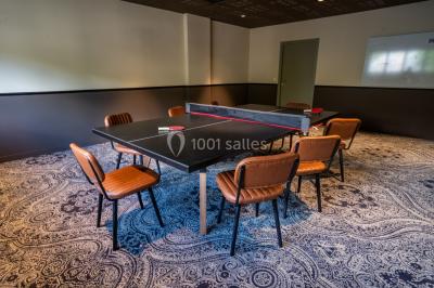 Salle de réunion avec table en bois foncé, six chaises grises, tableau blanc et écran mural.
