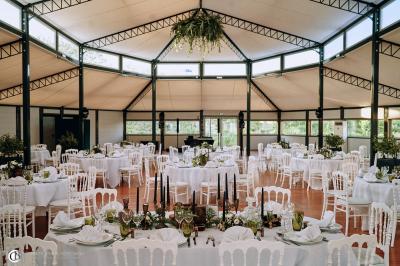 Salle de réception éclairée la nuit, avec des tables dressées visibles à travers les baies vitrées.