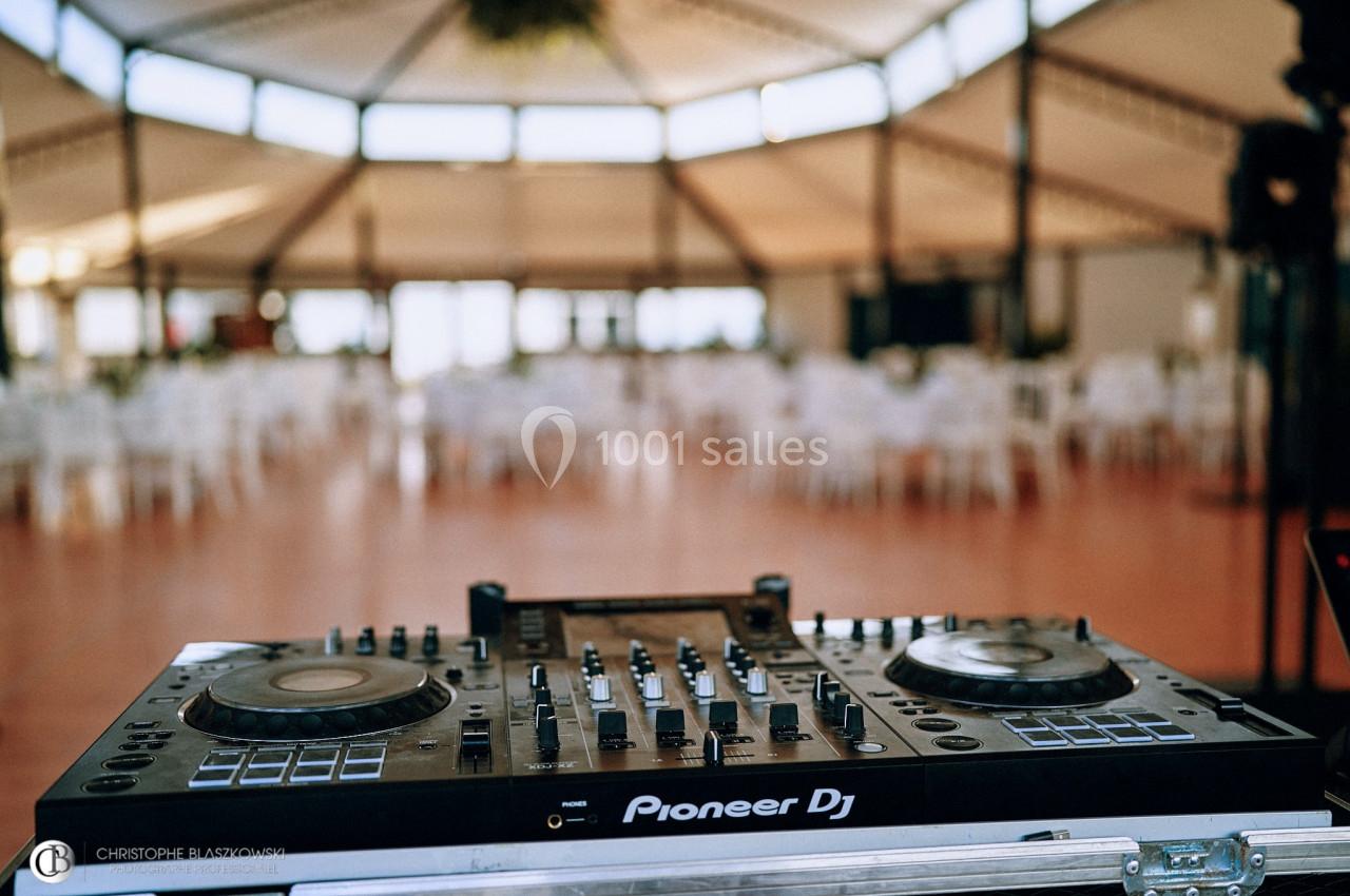 Table de mixage Pioneer DJ dans une salle de réception vide avec des chaises et des tables en arrière-plan.
