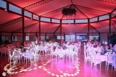 Salle de réception éclairée la nuit, avec des tables dressées visibles à travers les baies vitrées.