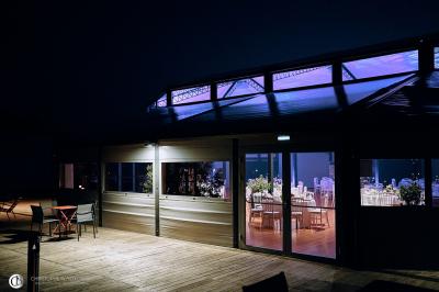 Salle de réception éclairée la nuit, avec des tables dressées visibles à travers les baies vitrées.