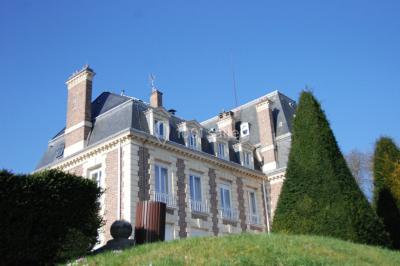 Coin cuisine moderne avec micro-ondes, cafetière, réfrigérateur, étagères en bois et horloge murale.