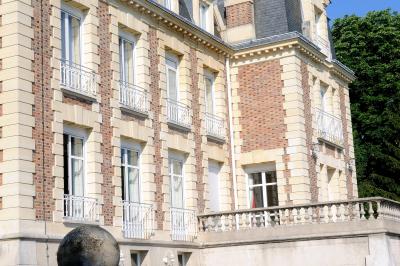 Coin cuisine moderne avec micro-ondes, cafetière, réfrigérateur, étagères en bois et horloge murale.