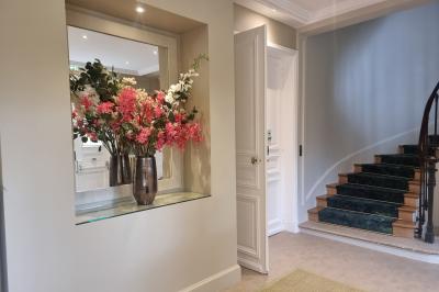 Coin cuisine moderne avec micro-ondes, cafetière, réfrigérateur, étagères en bois et horloge murale.