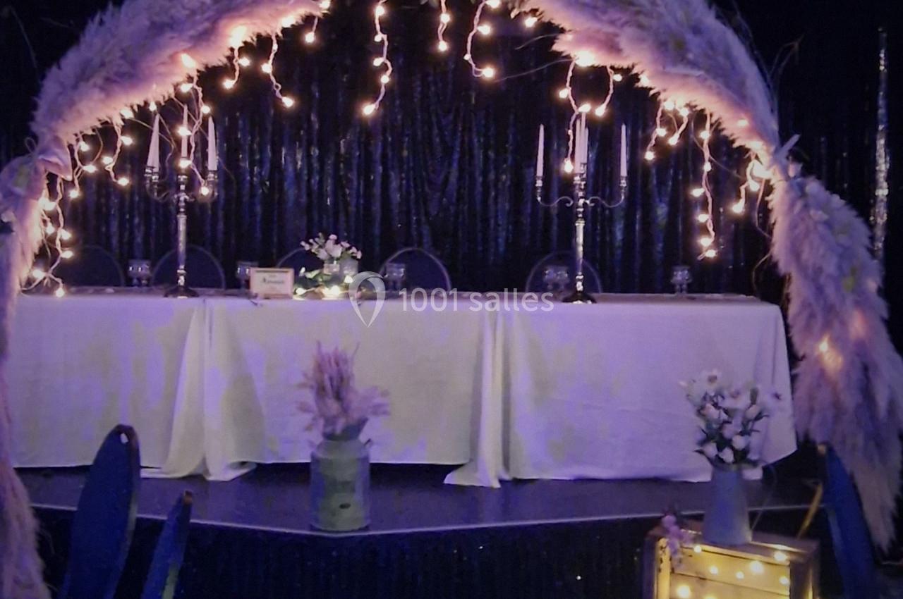 Arche décorative lumineuse avec pampas entourant une table de réception, ambiance festive et élégante.