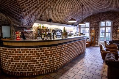 Salle de restaurant avec murs en briques, bar éclairé en arrière-plan et table dressée au premier plan.