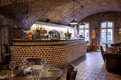 Salle de restaurant avec murs en briques, bar éclairé en arrière-plan et table dressée au premier plan.