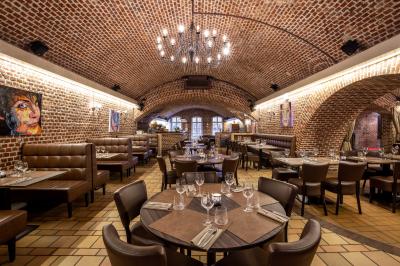 Salle de restaurant avec murs en briques, bar éclairé en arrière-plan et table dressée au premier plan.