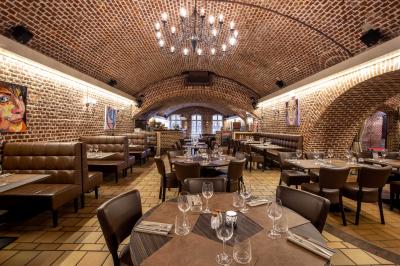 Salle de restaurant avec murs en briques, bar éclairé en arrière-plan et table dressée au premier plan.