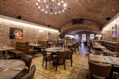 Salle de restaurant avec murs en briques, bar éclairé en arrière-plan et table dressée au premier plan.