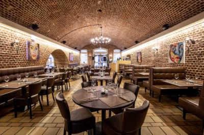 Salle de restaurant avec murs en briques, bar éclairé en arrière-plan et table dressée au premier plan.