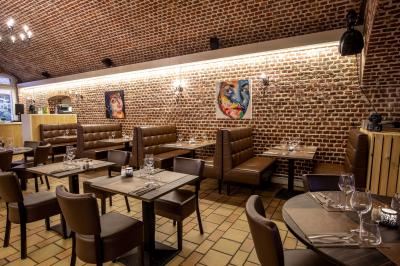 Salle de restaurant avec murs en briques, bar éclairé en arrière-plan et table dressée au premier plan.