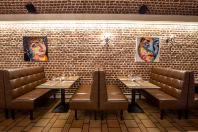 Salle de restaurant avec murs en briques, bar éclairé en arrière-plan et table dressée au premier plan.