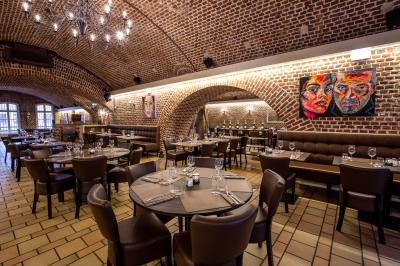 Salle de restaurant avec murs en briques, bar éclairé en arrière-plan et table dressée au premier plan.