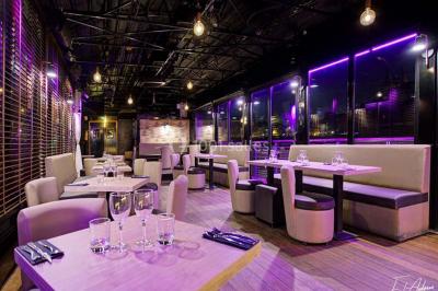 Salle de club vide avec éclairage bleu, miroirs sur les murs et bar en arrière-plan.