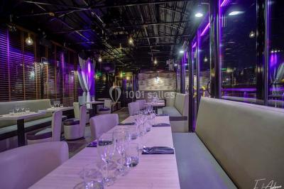 Salle de club vide avec éclairage bleu, miroirs sur les murs et bar en arrière-plan.