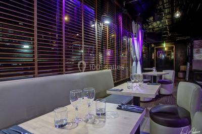 Salle de club vide avec éclairage bleu, miroirs sur les murs et bar en arrière-plan.