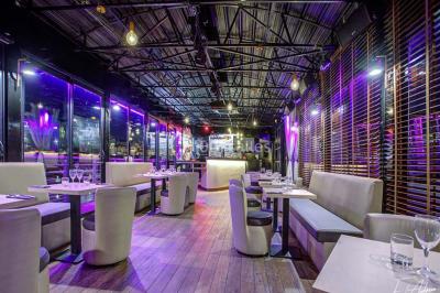 Salle de club vide avec éclairage bleu, miroirs sur les murs et bar en arrière-plan.