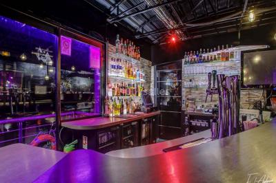 Salle de club vide avec éclairage bleu, miroirs sur les murs et bar en arrière-plan.