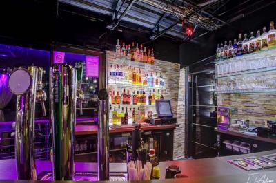 Salle de club vide avec éclairage bleu, miroirs sur les murs et bar en arrière-plan.