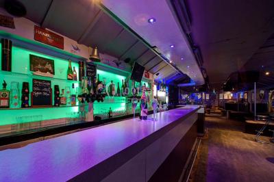 Salle de club vide avec éclairage bleu, miroirs sur les murs et bar en arrière-plan.