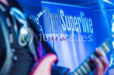 Un musicien joue du saxophone lors d'une réception festive dans une salle décorée avec des lumières et des drapés.