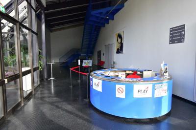 Salle spacieuse avec parquet en bois, grandes baies vitrées et quelques plantes en arrière-plan.