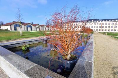 Bâtiment avec toit en tuiles et arcades, entouré d'une clôture métallique ornée de motifs végétaux.