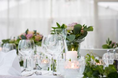 Table élégamment dressée avec verres, bougies allumées et compositions florales dans un cadre lumineux.