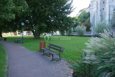Étang calme entouré d'arbres, avec des nénuphars flottant à la surface et une petite berge en pierre à droite.