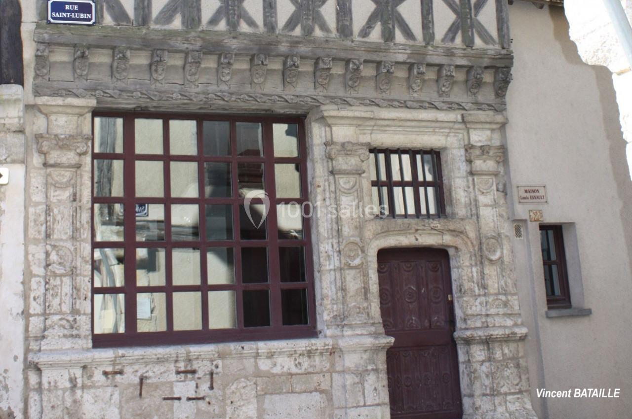 Façade d'une maison ancienne à colombages avec une porte sculptée et des fenêtres à petits carreaux.