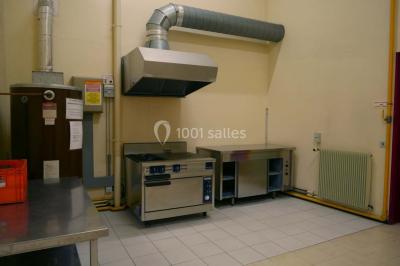 Salle de service avec éviers en inox, armoires rouges, échelle et murs beige clair.