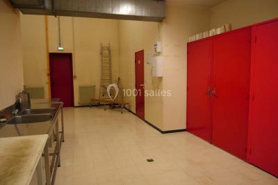 Salle de travail avec éviers en inox, armoires rouges, échelle et murs beige clair.