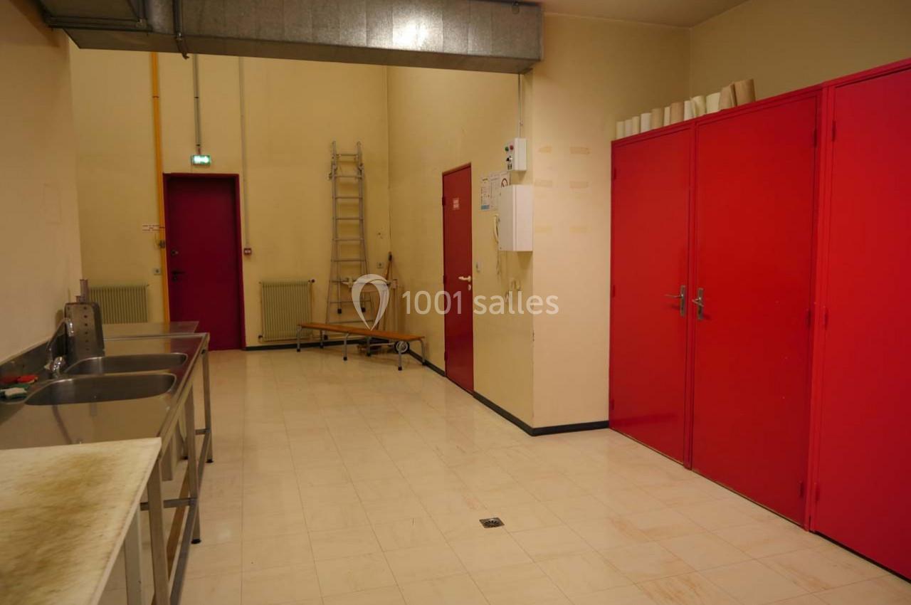 Salle de travail avec éviers en inox, armoires rouges, échelle et murs beige clair.