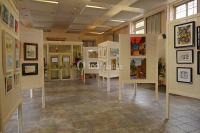 Entrée vitrée d'un bâtiment avec des plantes en pot et des peintures accrochées aux murs.