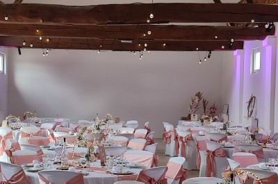Allée en gravier bordée d'un bâtiment en bois et briques, décorée de fleurs et de voilages blancs.