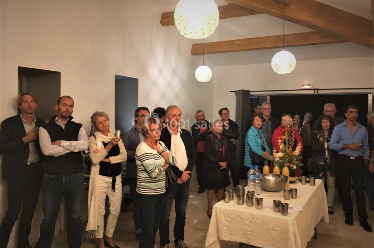 Un groupe de personnes rassemblées dans une salle éclairée, près d'une table dressée avec des boissons et des décorations.
