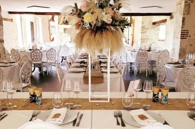 Bouquet de fleurs blanches et vertes au premier plan, avec des chaises disposées en extérieur sous un grand arbre.