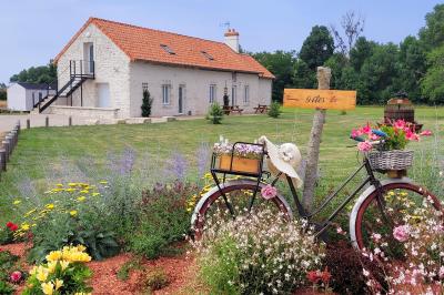 Bouquet de fleurs blanches et vertes au premier plan, avec des chaises disposées en extérieur sous un grand arbre.