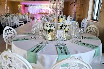 Bouquet de fleurs blanches et vertes au premier plan, avec des chaises disposées en extérieur sous un grand arbre.