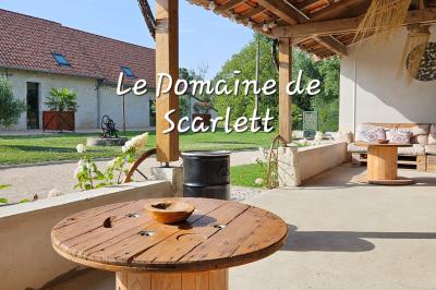 Bouquet de fleurs blanches et vertes au premier plan, avec des chaises disposées en extérieur sous un grand arbre.