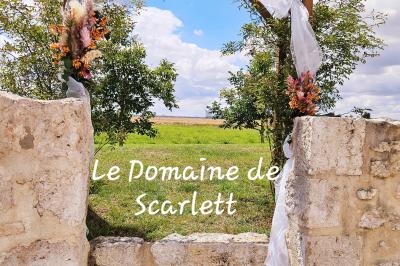 Bouquet de fleurs blanches et vertes au premier plan, avec des chaises disposées en extérieur sous un grand arbre.