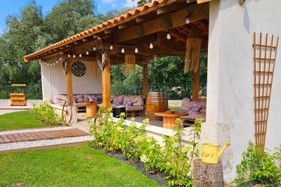 Bouquet de fleurs blanches et vertes au premier plan, avec des chaises disposées en extérieur sous un grand arbre.